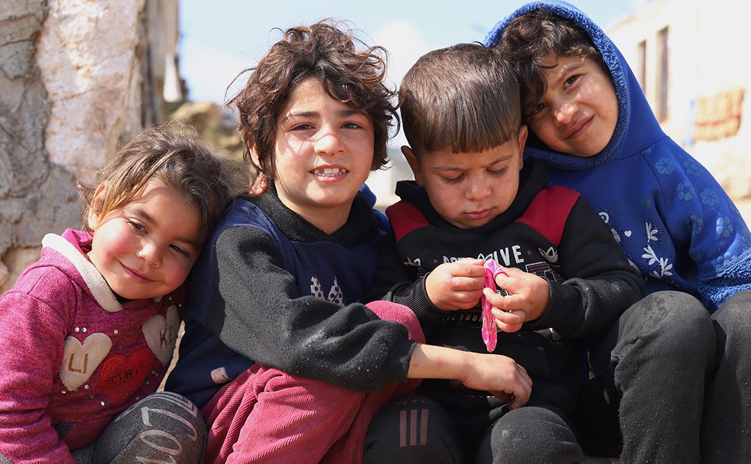 Four children sitting in front of their family's shelter in a camp for displaced people in Kelly, Idleb, Northwest Syria