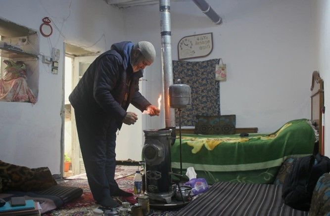 Suleiman firing up the gas stove to warm his room