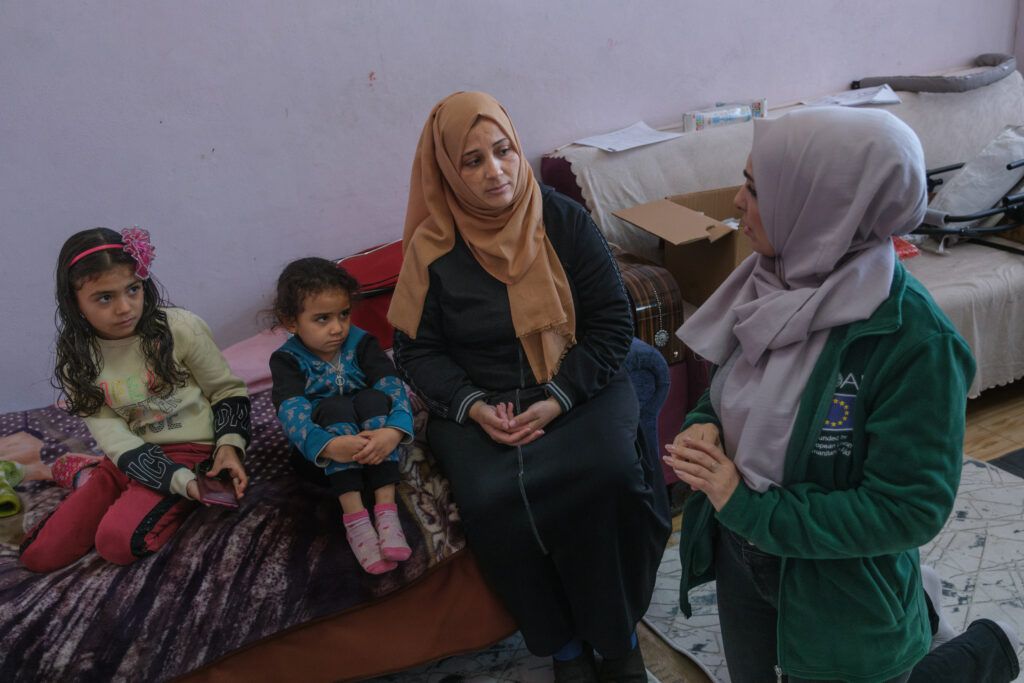 Aisha, with her two young children speaking with a GOALie.